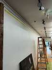 a white wall with a ladder and a painting on it